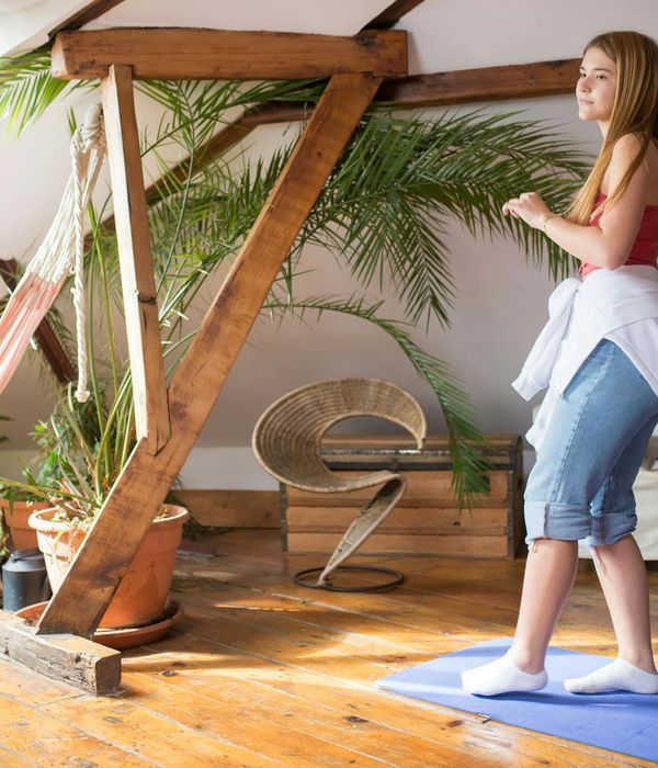 Woman performing a gentle, energetic movement in a bright space.